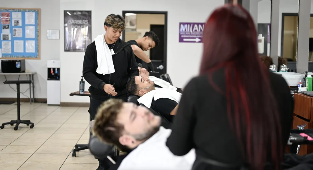 Barber students in Bakersfield, California practice close shaves on the salon floor.